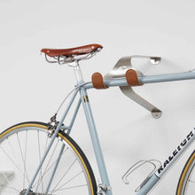 Load image into Gallery viewer, Cactus Tongue SSL bike hanger with brown leather sleeves holding a classic steel bike.