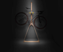 Load image into Gallery viewer, A titanium road bike hanging on a Cactus Tongue Wishbone wall stand dramatically lit by a beam of light from above