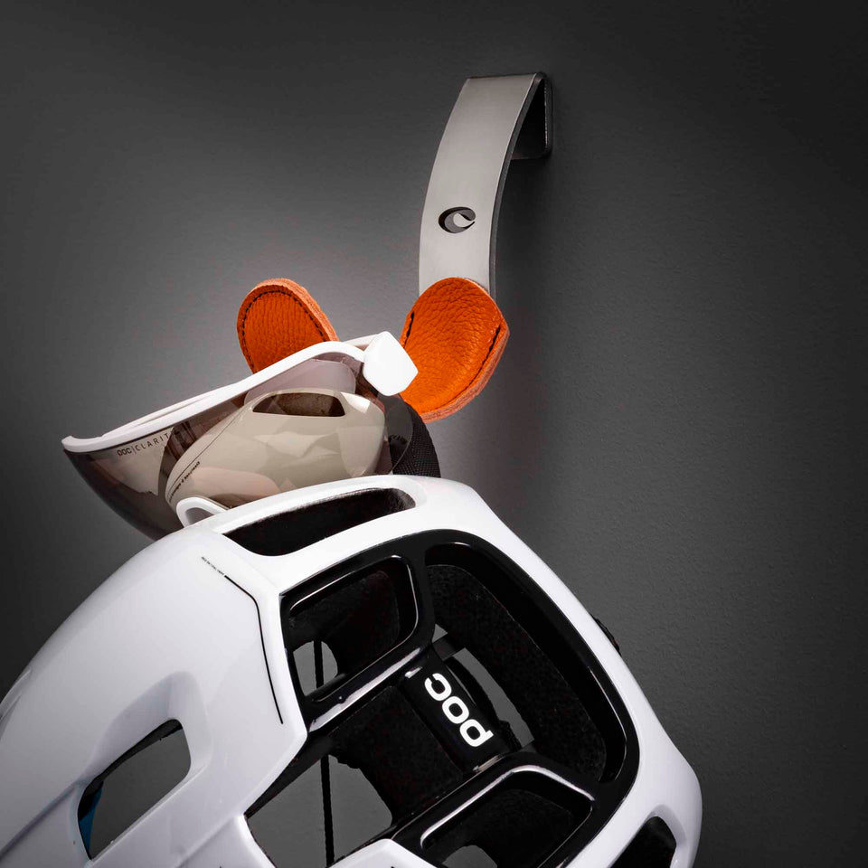 A white POC cycling helmet and sunglasses hanging on an orange Cactus Tongue Scoop Accessories hanger.