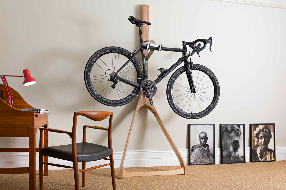  Black Colnago road bike hanging on a Cactus Tongue wishbone wall stand, against a living room wall.